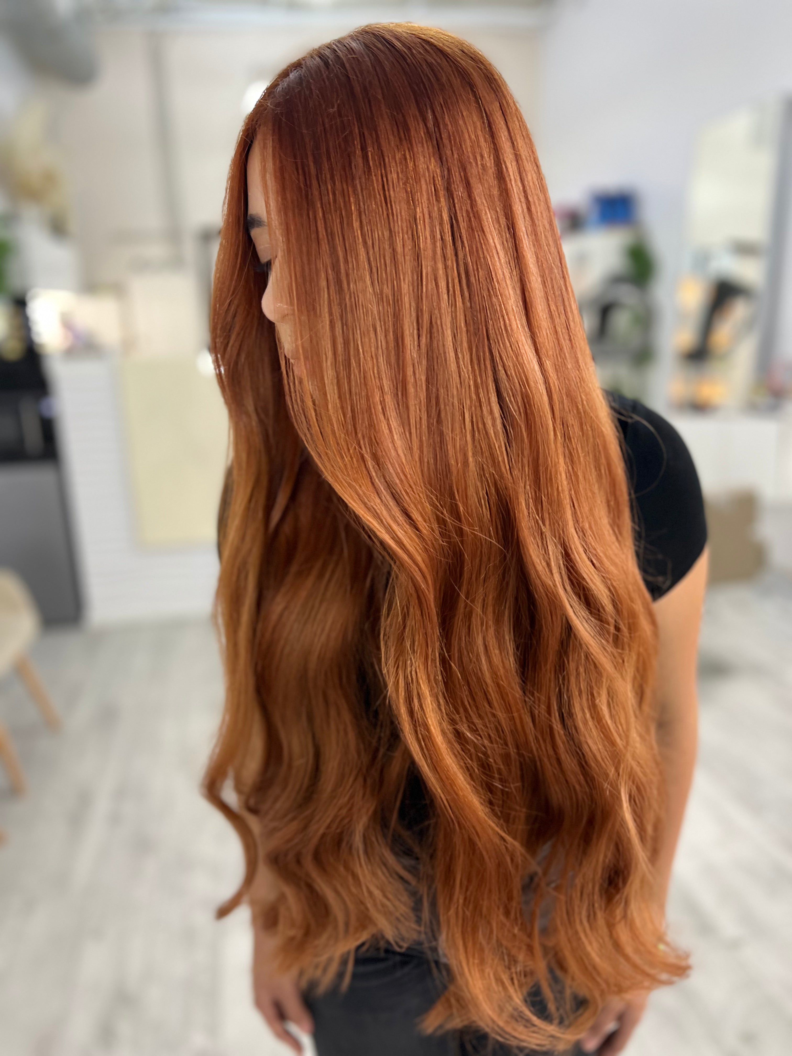 Persona con cabello largo, ondulado y castaño rojizo en un salón de belleza.