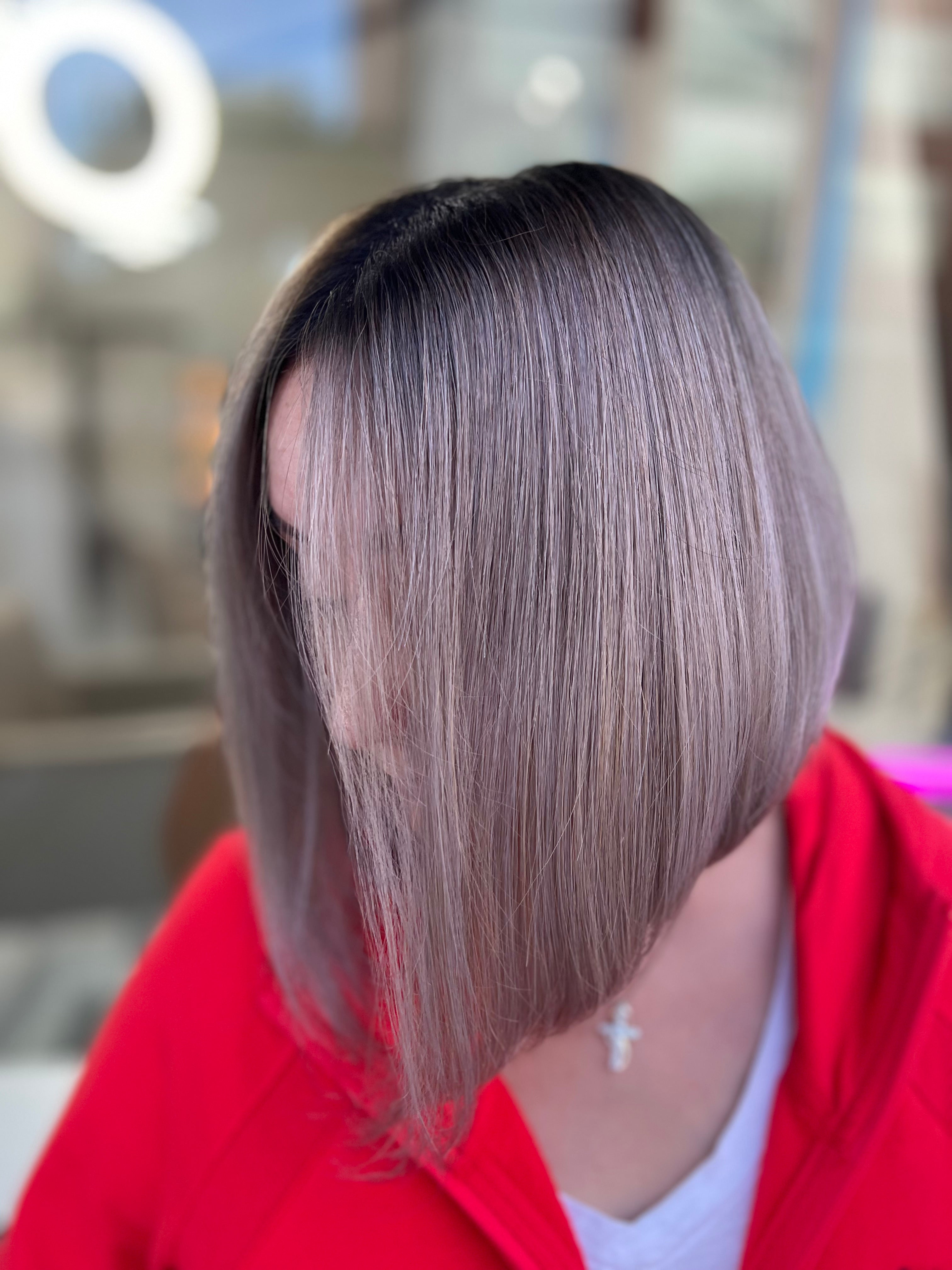 Persona con cabello gris que lleva una blusa roja en un ambiente interior con fondo borroso.