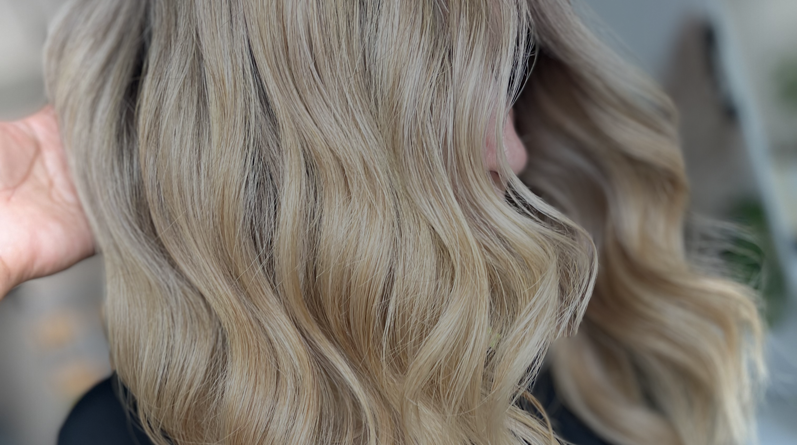 Primer plano de cabello rubio ondulado con fondo desenfocado.