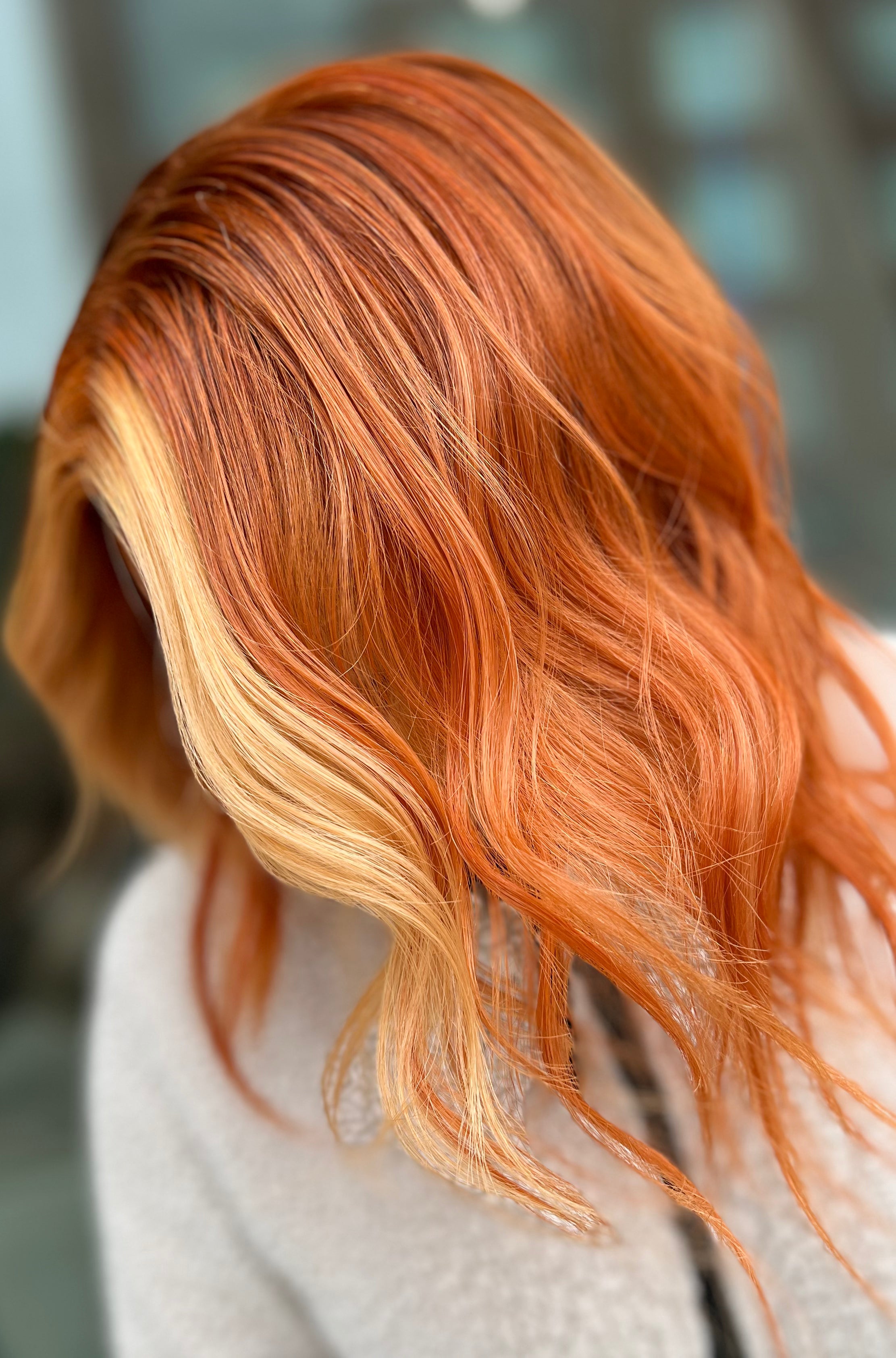 Primer plano de cabello ondulado con tonalidades naranjas y rubias.