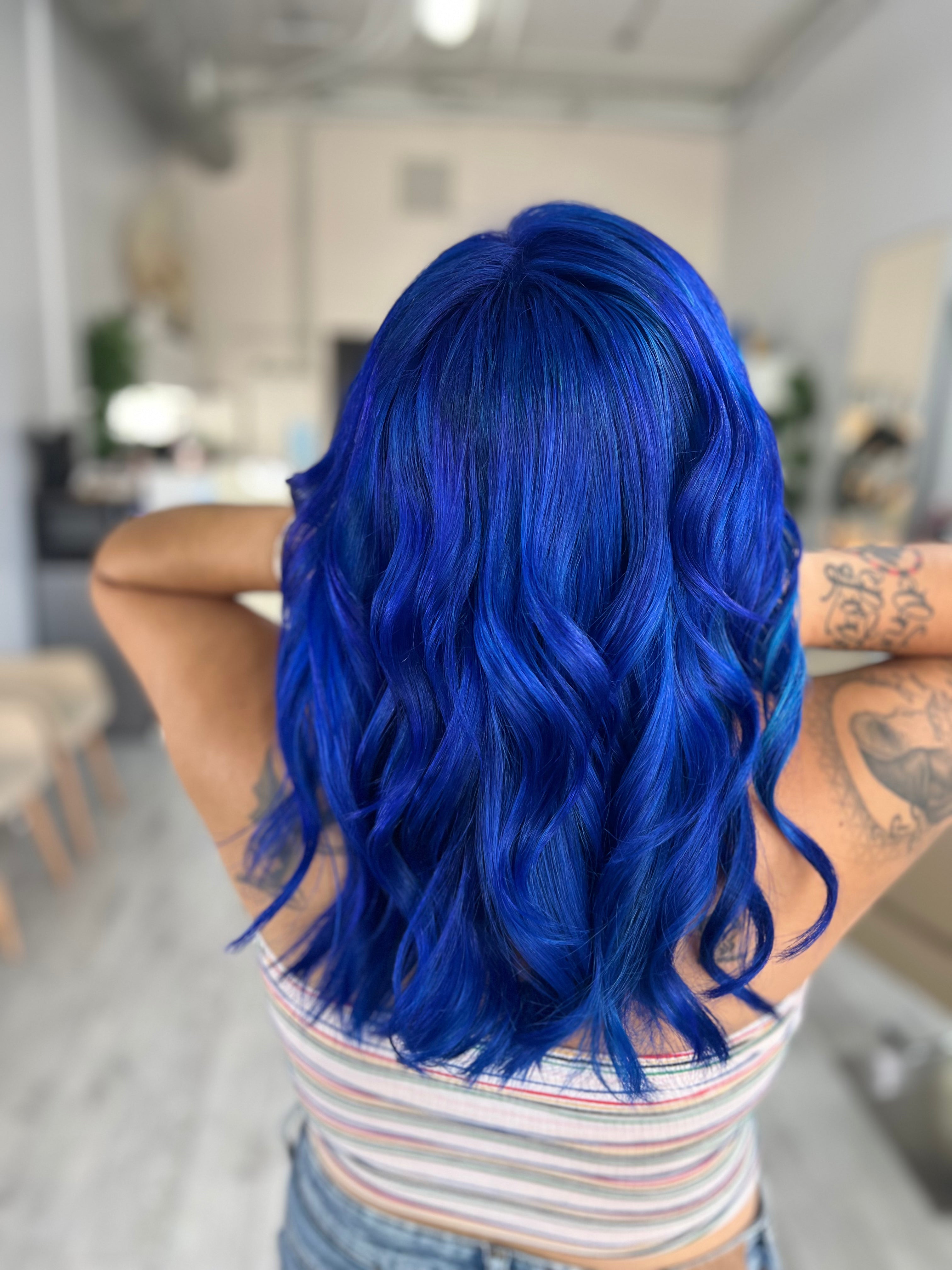 Persona con cabello azul vibrante en un entorno de peluquería.