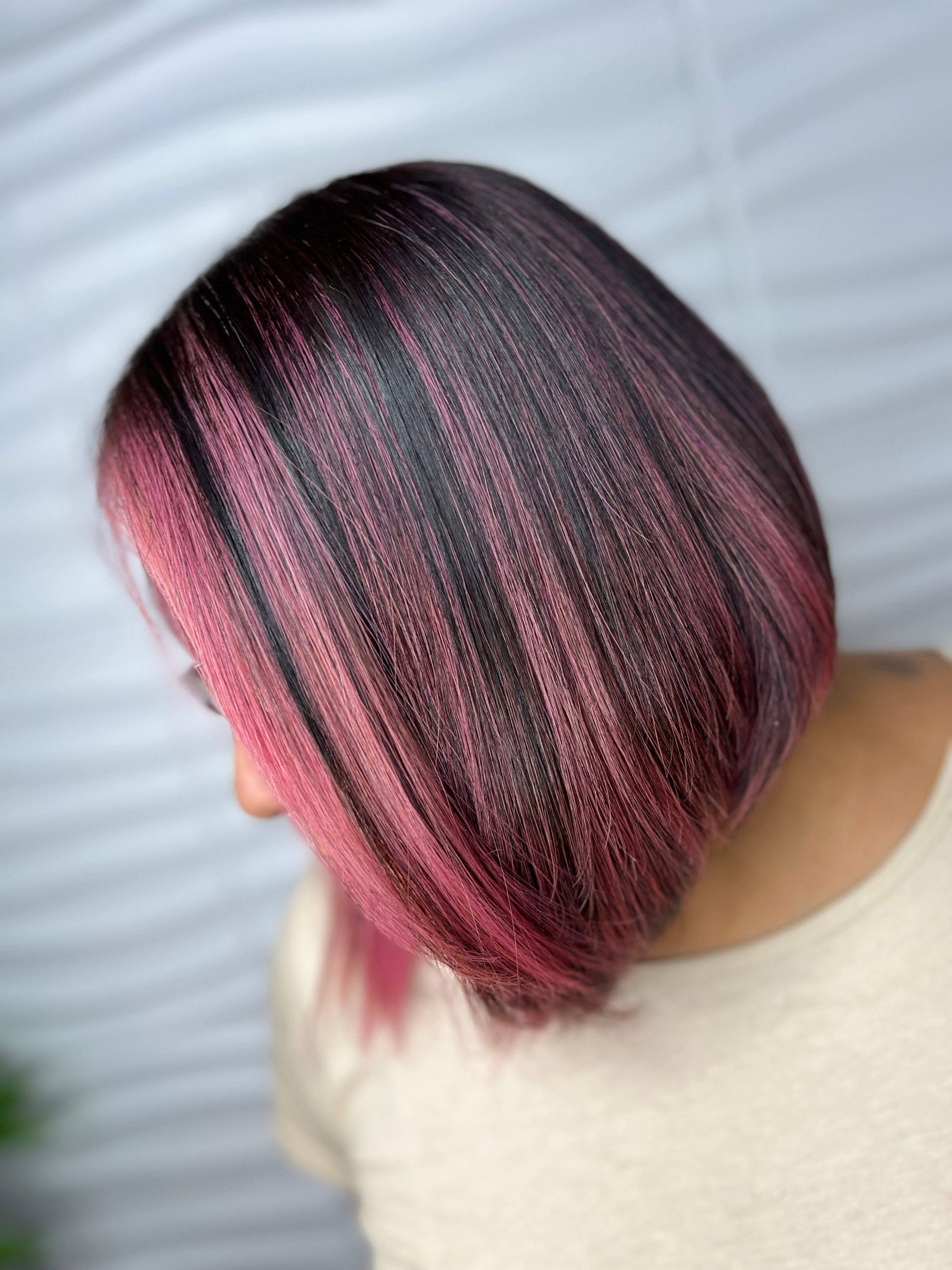Persona con un corte de pelo elegante que incluye cabello negro y rosa.