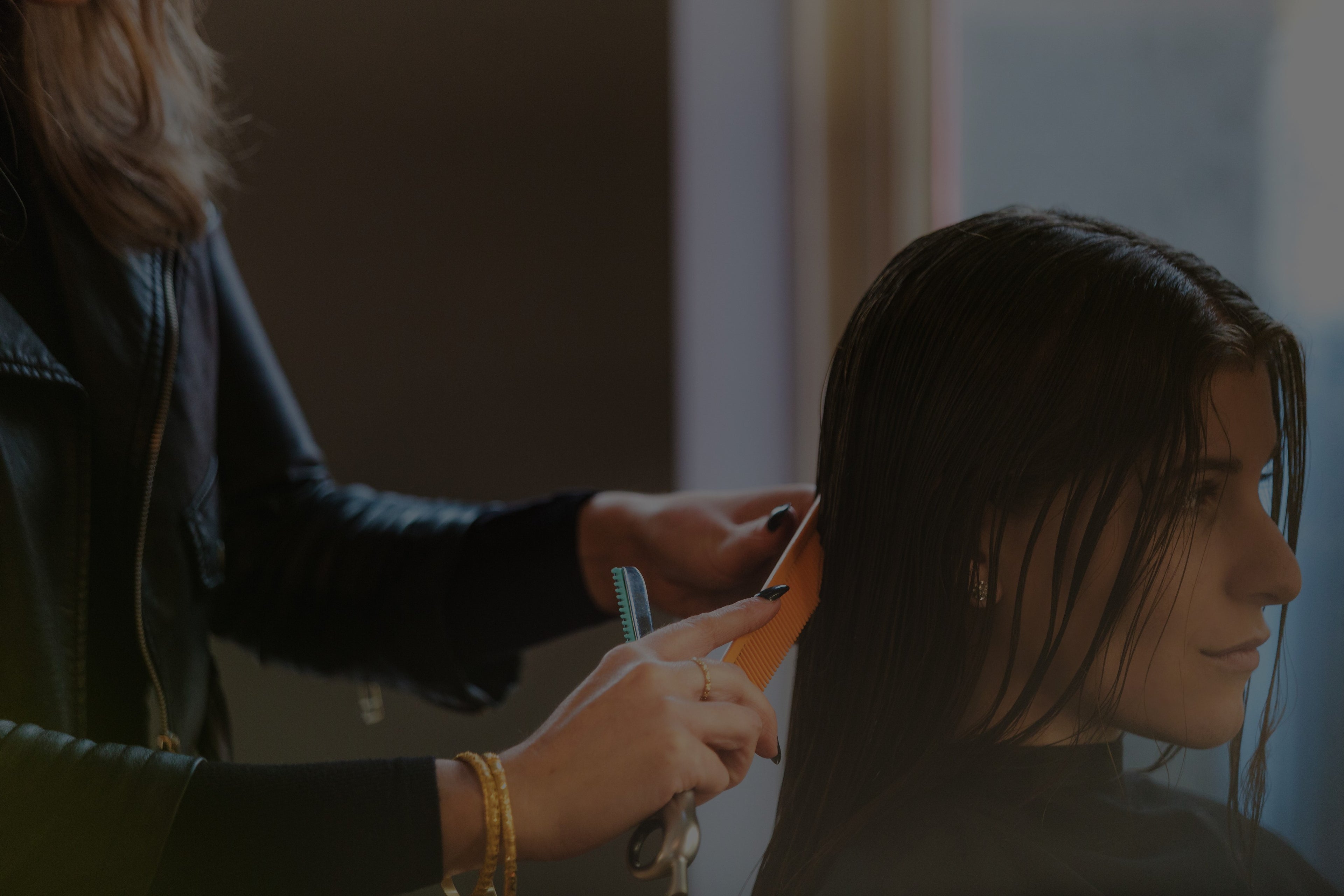 Persona recibiendo un corte de pelo con tijeras por parte de un estilista en un salón de belleza.