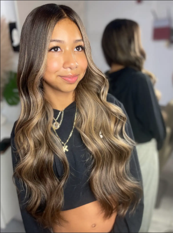 Mujer con cabello largo y ondulado en un salón de belleza.